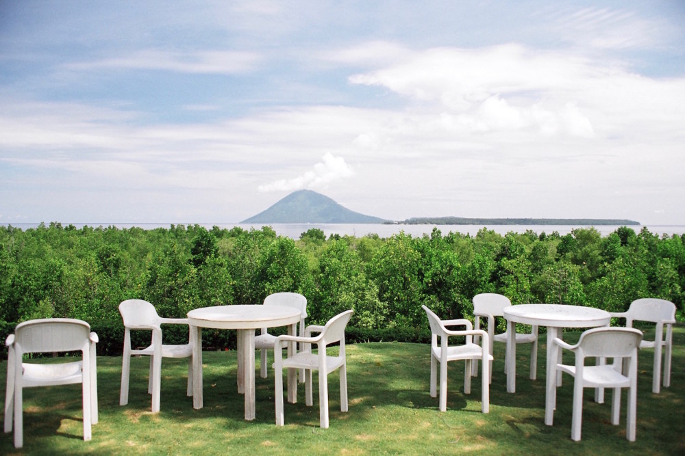 Plastic tables and chairs, mangrove trees and Bunaken island
